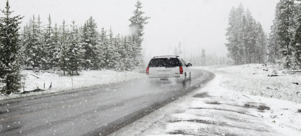 A car driving in the snow in the evening, driving a bit too fast to be safe.